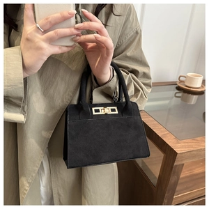 Gros plan du sac en daim noir avec boucle dorée et détail de manteau chic français