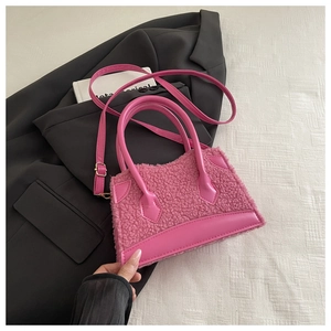 Vue détaillée du mini sac à main en peluche rose sur un blazer noir avec bandoulière réglable