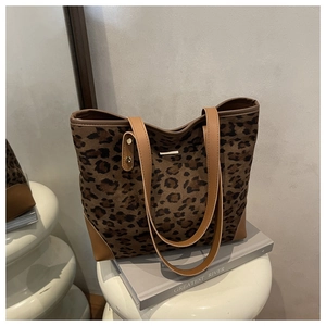 Detail view of leopard print tote bag with brown straps on a white table