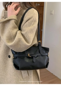 Dettaglio di una borsa tote retrò nera con fibbia vintage su un cappotto di lana beige