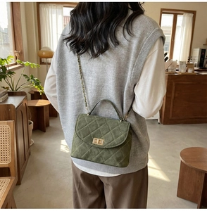 Detail of olive green quilted suede crossbody bag with gold metal twist lock and chain strap