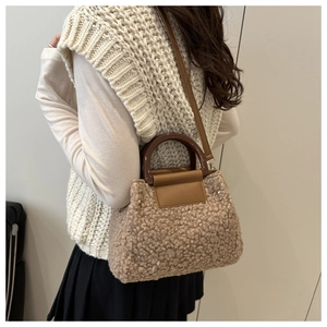 Detail of plush lambskin-like tote with resin handle and leather strap on model