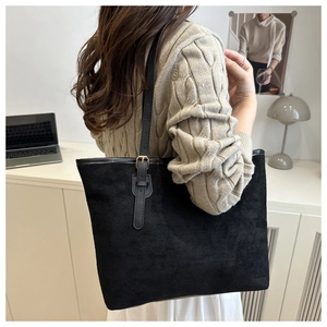 Detail of minimalist black tote bag with slender leather strap and gold metal buckle