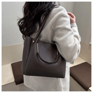 Detail of dark brown lychee leather bucket bag with elegant curved gold metal handle