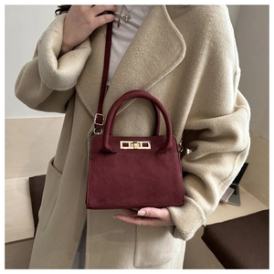 Dettaglio borsa bordeaux in pelle opaca con fibbia dorata su sfondo cappotto beige