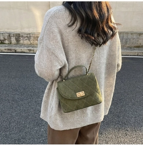 Detail of dark green quilted suede bag featuring gold twist lock and chain strap texture