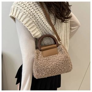 Detail of brown plush faux shearling crossbody bag with dark leather handle and strap