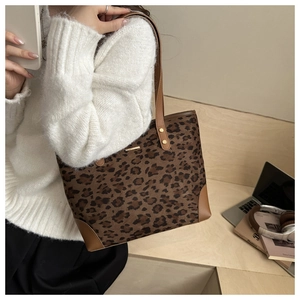Detailed close-up of leopard print tote bag featuring brown leather trim and gold rivets