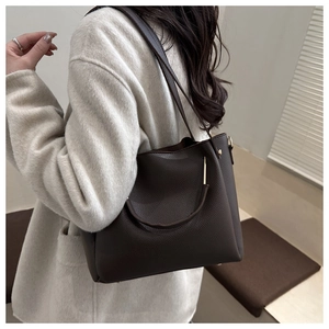 Dettaglio borsa shopper in pelle martelliccia marrone scuro con fibbie dorate su cappotto bianco