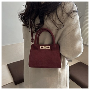 Dettaglio borsa tote in pelle scamosciata bordeaux con chiusura a rotazione dorata