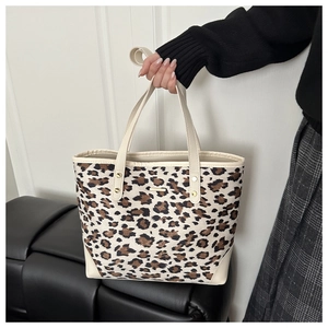 Detail of leopard print tote bag featuring cream PU handles and golden metal rivets