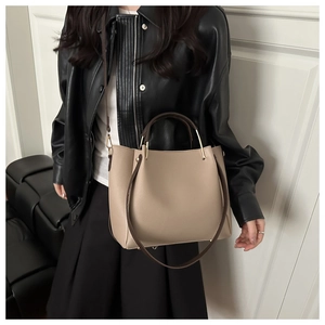 Detail of lychee pattern leather tote with golden hardware and contrast strap