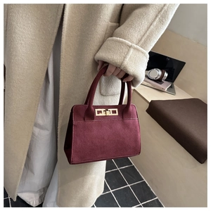 Dettaglio borsa bordeaux in finto scamosciato con fibbia dorata su un cappotto beige