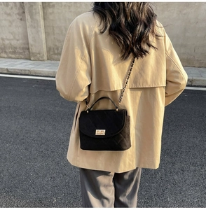 Detail of black quilted leather handbag with gold twist lock and chain strap on outfit
