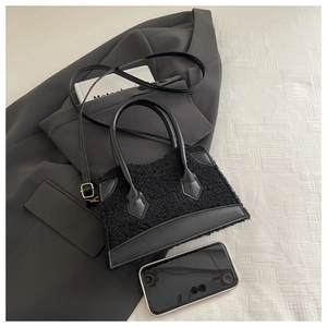 Détail d'un sac en peluche noire avec finitions cuir sur fond texturé élégant