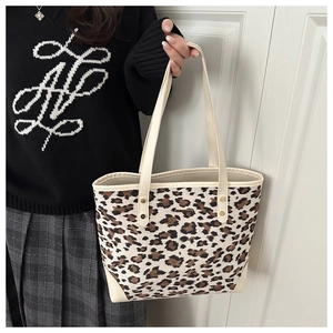 Detail of leopard print tote bag featuring cream leather straps and golden rivet accents