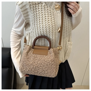 Close-up of a brown fleece bucket bag featuring wooden handles and leather flap detail