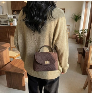 Quilted dark brown crossbody bag with gold buckle shown in a vintage cafe setting