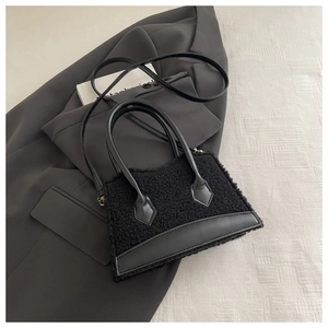 Détail d'un sac à main en peluche noire avec lanières en cuir et boucles métalliques chic