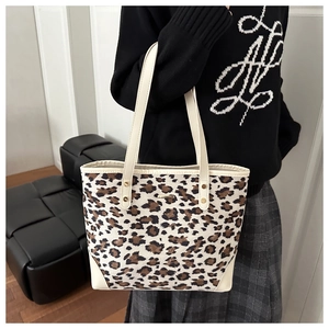 Detail of leopard print tote bag with white leather straps and gold rivet accents