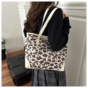 Detail of leopard print canvas tote bag with reinforced leather corners and metal studs