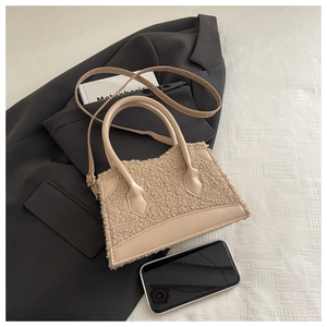 Détail du sac à bandoulière en peluche beige avec finitions en cuir sur blazer gris