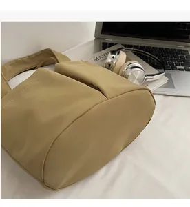 Détail du sac à bandoulière en nylon kaki souple dans un décor moderne lifestyle