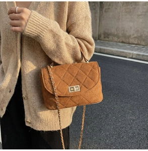 Detail of caramel quilted suede crossbody bag with gold chain strap and turn-lock closure