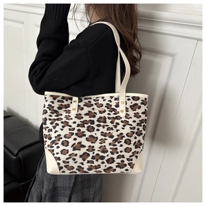 Detail of leopard print tote bag showing metal logo plaque and reinforced leather corners