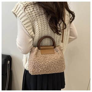 Detail of oatmeal textured fleece handbag with dark brown handles and leather strap