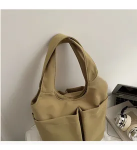 Détail du sac fourre-tout en nylon kaki avec poches avant et surpiqûres contrastées
