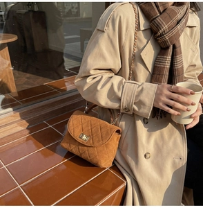 Brown quilted suede handbag with gold turn-lock and chain strap on a trench coat model