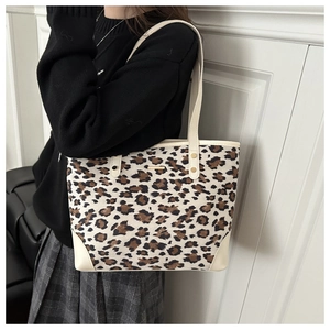 Macro view of leopard print tote bag featuring a metallic logo plate and reinforced corners
