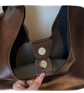 Detail of premium brown faux leather bag featuring double magnetic metal closures on inner rim
