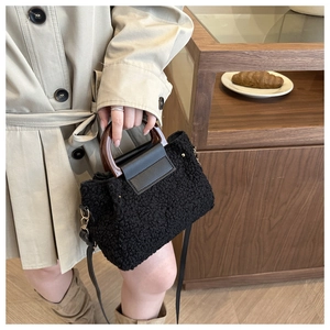 Detail of black teddy fleece bucket bag with amber handle and leather strap on model