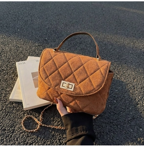 Close-up of suede crossbody bag with rhombus stitching, gold lock and chain strap