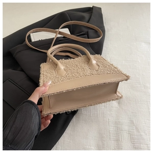 Detail of beige faux shearling handbag showing soft texture and leather strap attachment