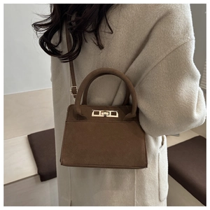 Dettaglio di una borsa a trapezio in pelle scamosciata marrone con chiusura dorata