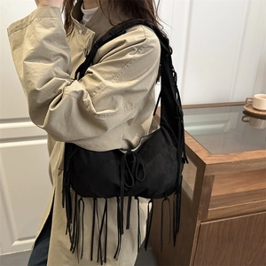 Bohemian black suede crescent shoulder bag with long fringe tassels worn by a model