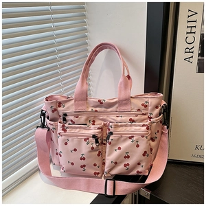 Détail du sac cabas en toile rose avec motifs cerises et multiples poches zippées