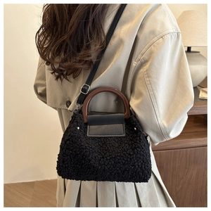 Detail of black faux fur handbag with wooden handle and adjustable shoulder strap