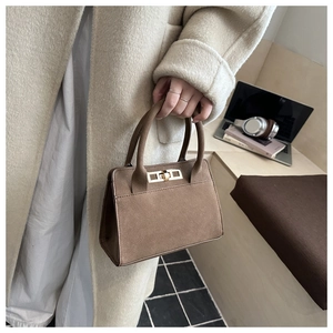 Détail du sac Kelly en daim marron foncé avec boucle métallique dorée en décor intérieur