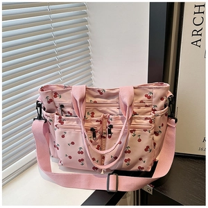 Détail du sac rose à motif cerise avec plusieurs poches zippées et anses en tissu