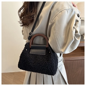 Gros plan d'un sac bandoulière noir en faux mouton avec poignée et sangle en cuir