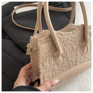 Gros plan sur la texture en laine d'agneau et la poignée en cuir lisse d'un sac élégant