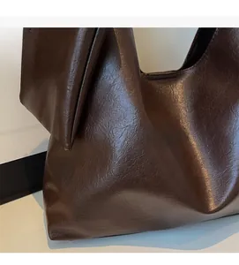 Detail showing the retro glossy texture and soft leather-like material of the brown tote bag