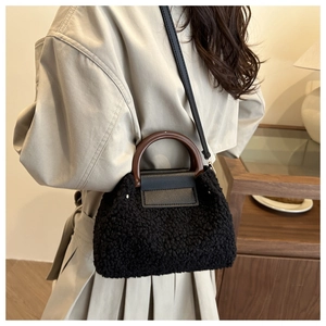 Detail of black faux shearling handbag with vintage round wooden handles and crossbody strap