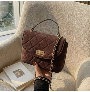 Detail of dark brown quilted suede handbag with gold turn-lock and chain strap