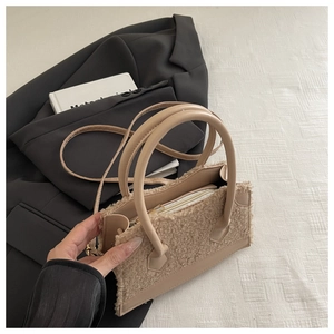 Détail d'un sac à main beige en peluche et similicuir avec double poignée et fermeture