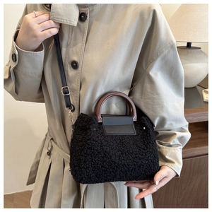 Detailed macro view of black plush crossbody bag featuring brown round handle and strap